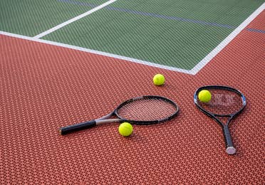 Two tennis rackets and three tennis balls laying on tennis court at Fox River Resort in Sheridan, Illinois.