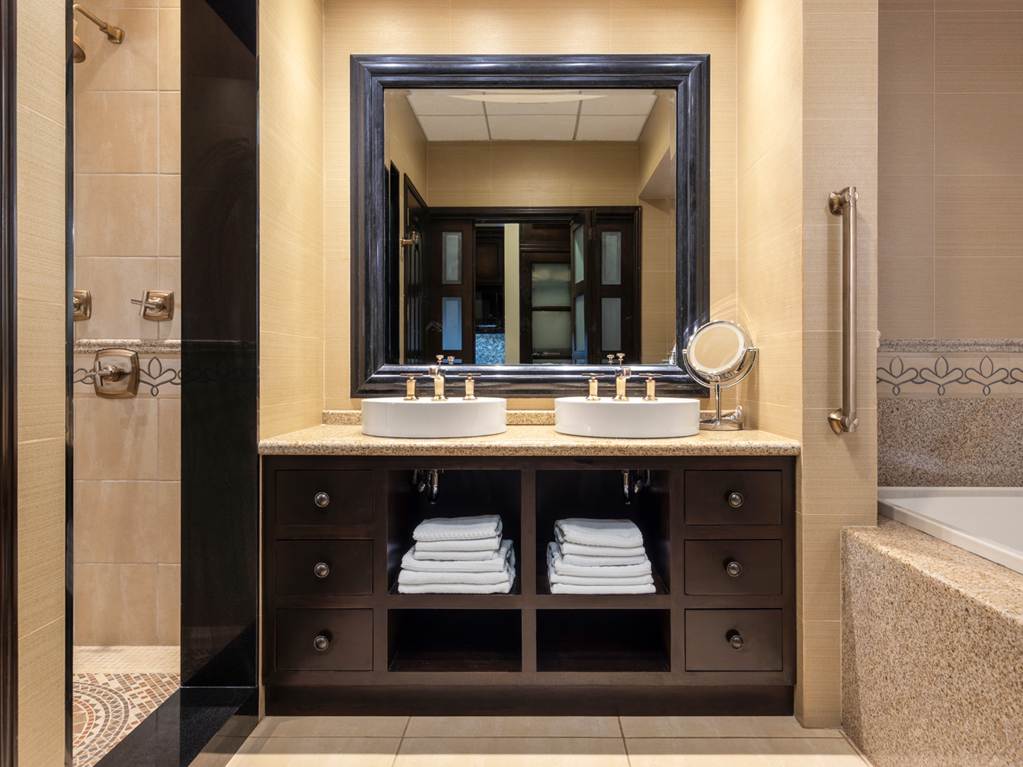 Elegant bathroom with dual sinks beside tiled tub and shower.