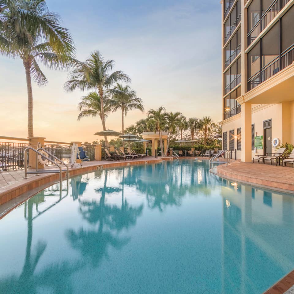 Outdoor pool surrounded by palm trees at Sunset Cove Resort