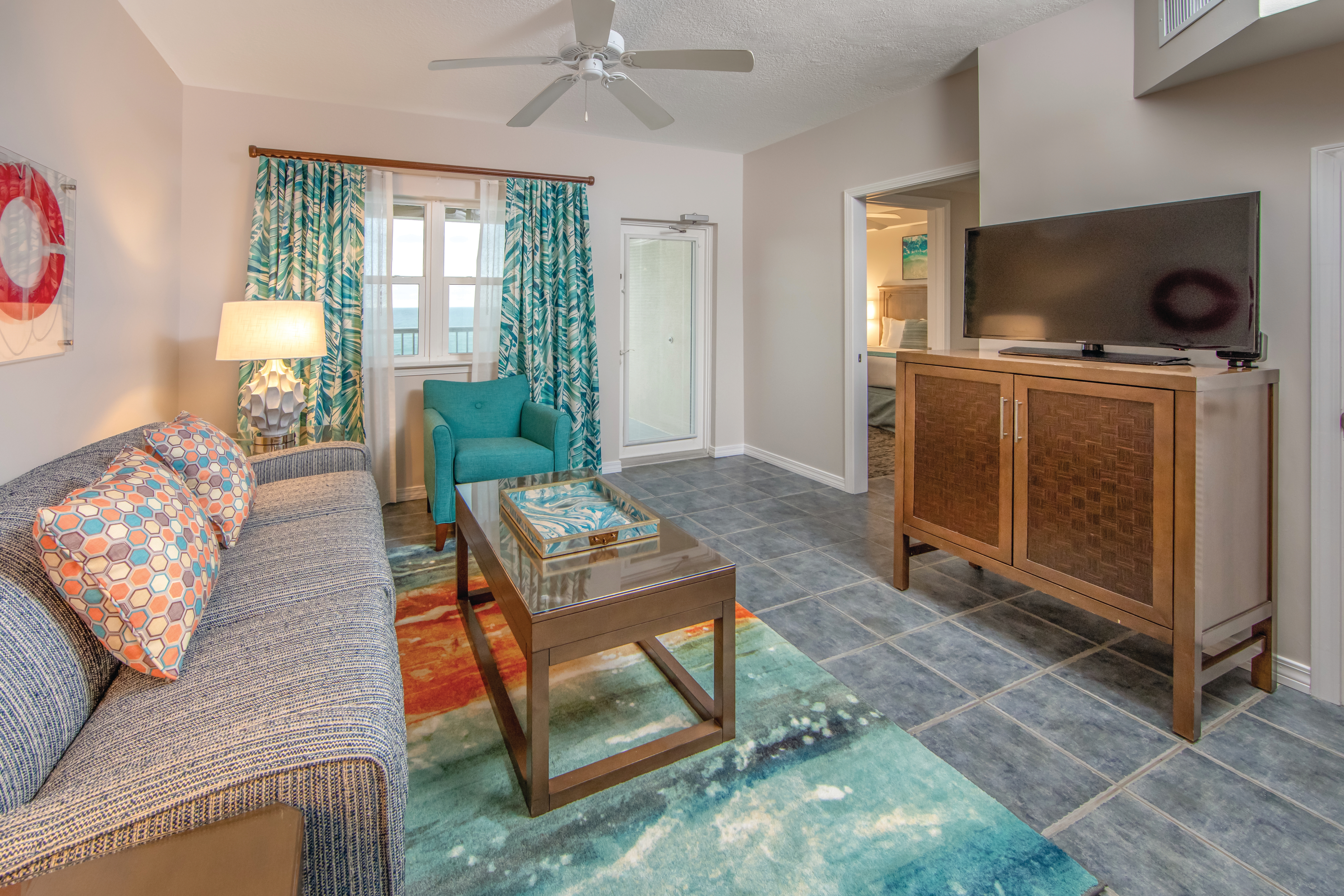 Living room with couch, accent chair, and flat screen TV in a one-bedroom villa at Panama City Beach Resort