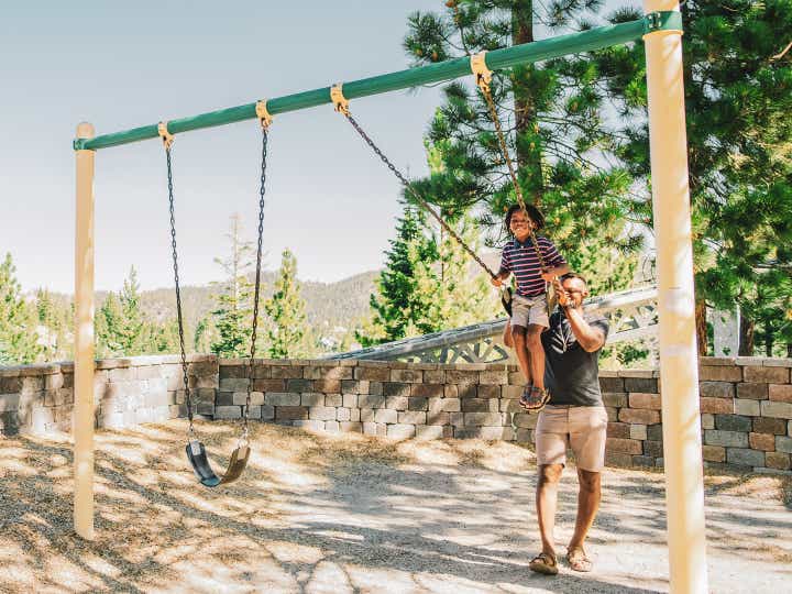 Father pushing child on swing at Tahoe Ridge Resort in Stateline, Nevada.