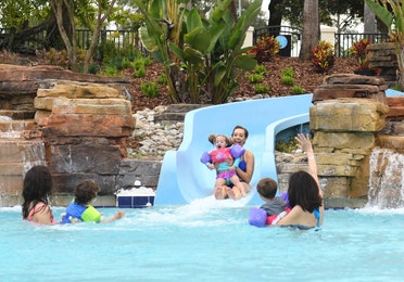 Mom and young girl sliding down water slide at Orange Lake Resort near Orlando, Florida