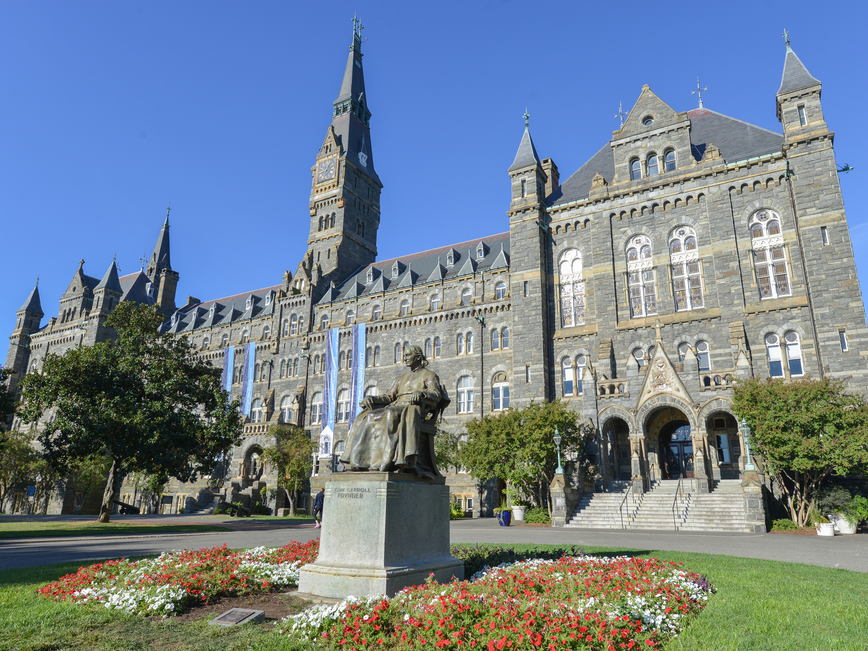 Historic Georgetown University building with a clock tower and statue in Washington, D.C. 