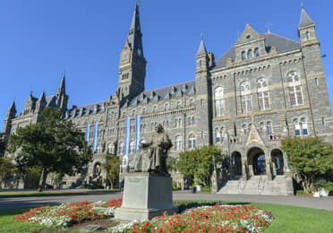 Historic Georgetown University building with a clock tower and statue in Washington, D.C.