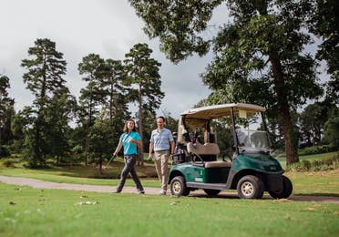 Couple standing next to golf cart on golf course at Eagle's Bluff Country Club near Villages Resort in Flint, Texas.