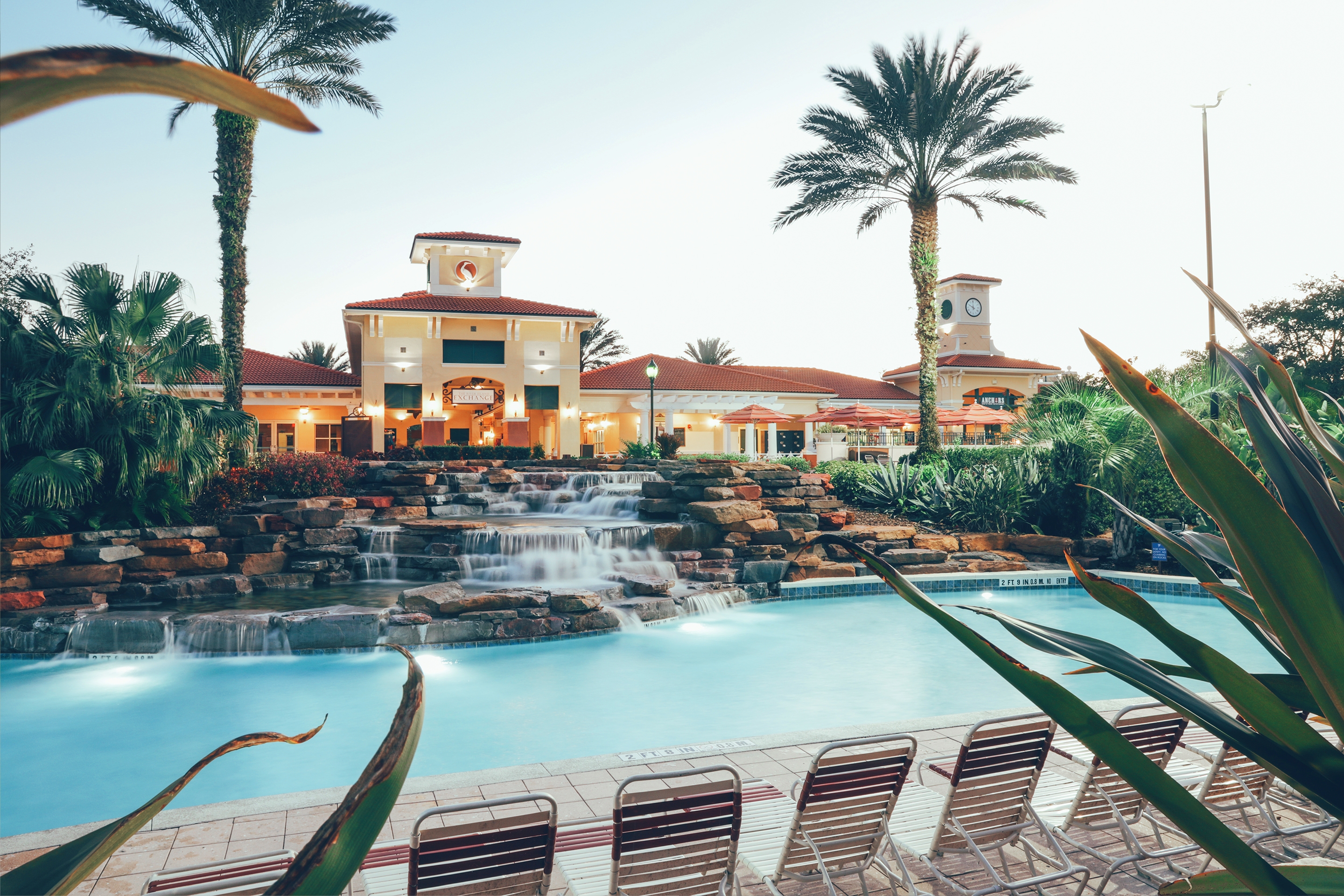 A building stands behind a lazy river and waterfall feature.