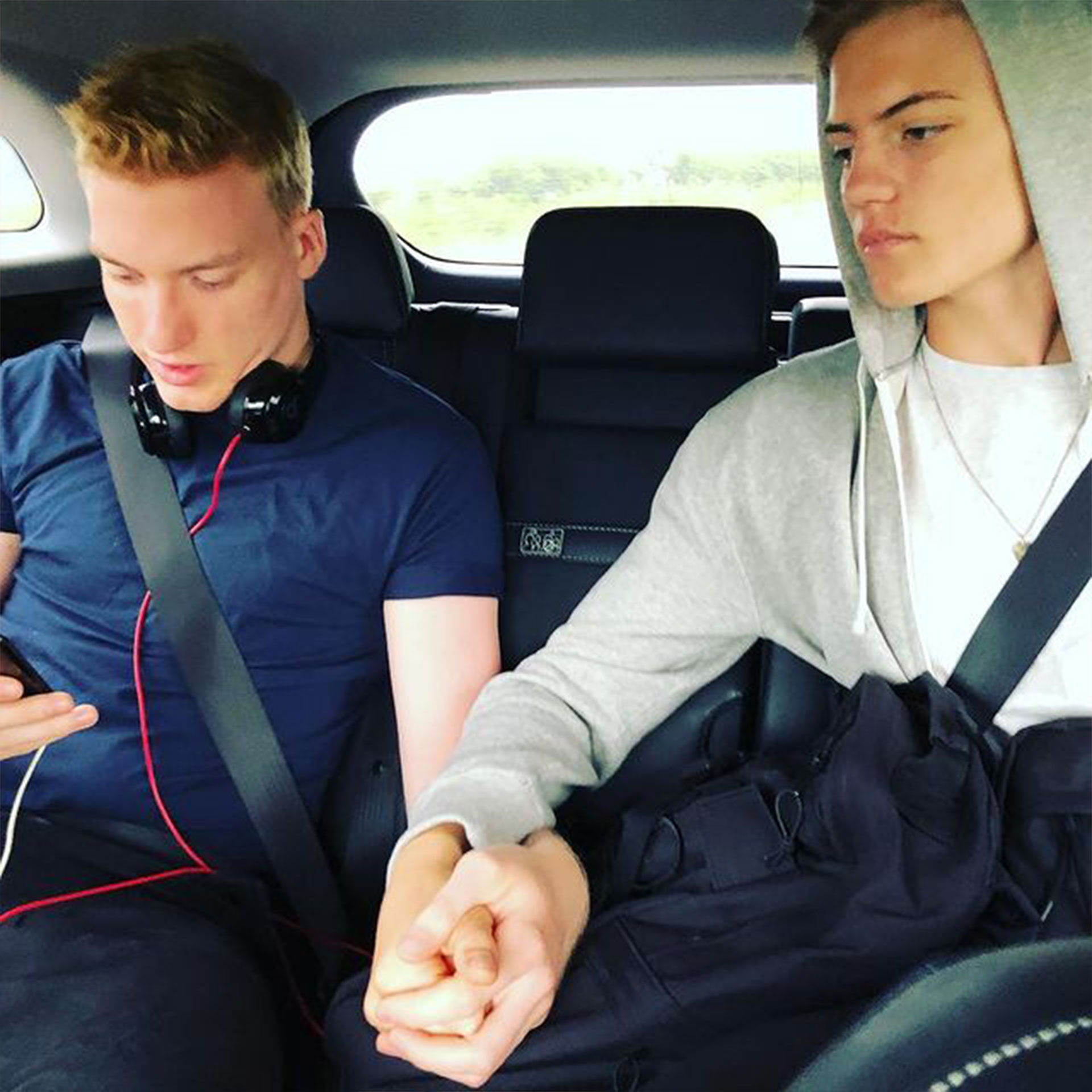 Featured Contributor, Ninka-Bernadette Mauritson's sons hold hands while driving in the backseat of a car.