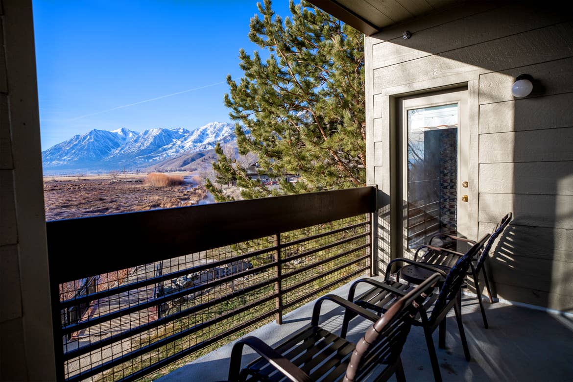 A balcony with two patio chairs overlooks a mountain range.
