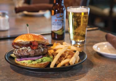 A hamburger, french fries and hard cider in a glass from The Maple Kitchen at Mount Ascutney Resort