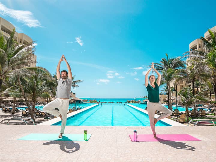 Couple doing yoga by the pool at Royal Sands Resort in Cancun Mexico.