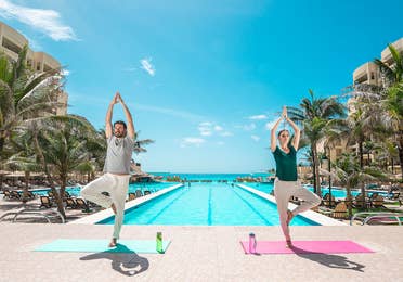 Couple doing yoga by the pool at Royal Sands Resort in Cancun Mexico.