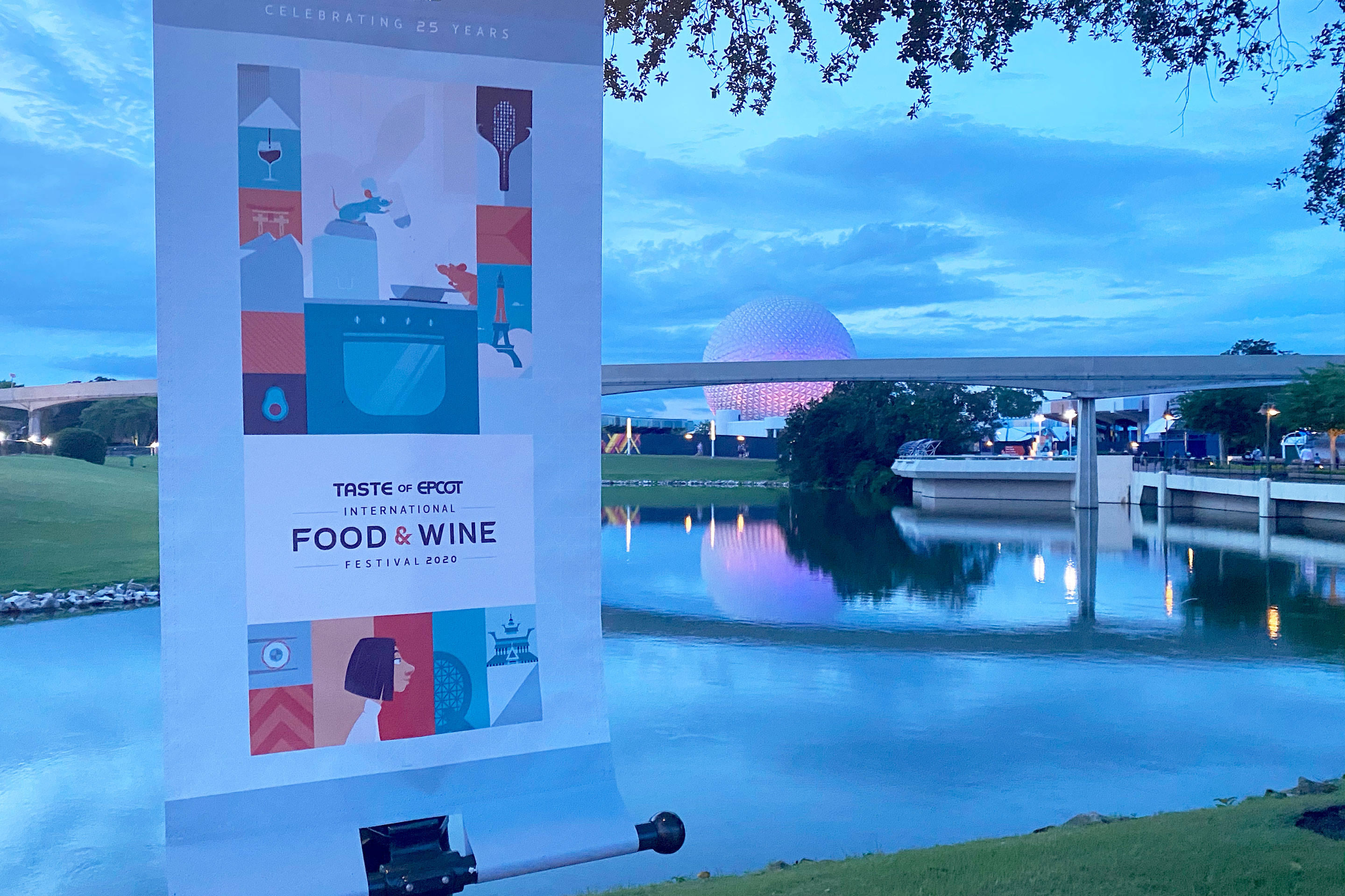 Taste of EPCOT International Food & Wine Festival banner stands on a post as Future World at EPCOT can be seen in the background.