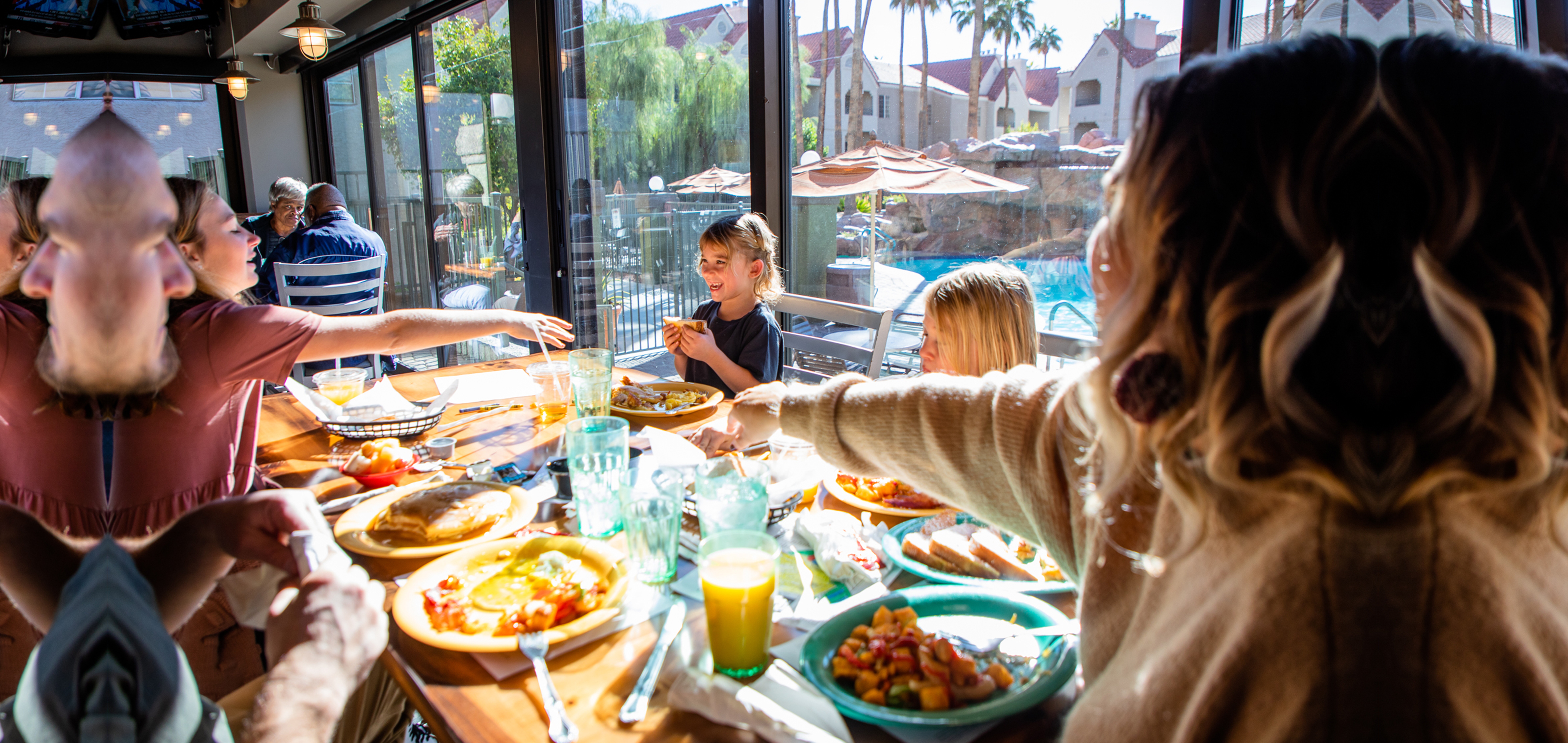 Family eating breakfast at Gold Mine Bar & Grill with pool view at Desert Club Resort in Las Vegas, Nevada.