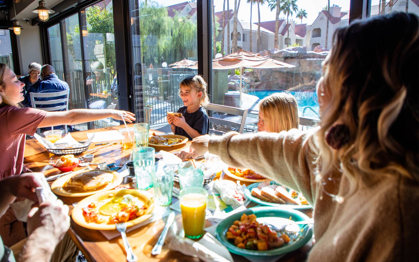 Family eating breakfast at Gold Mine Bar & Grill with pool view at Desert Club Resort in Las Vegas, Nevada.