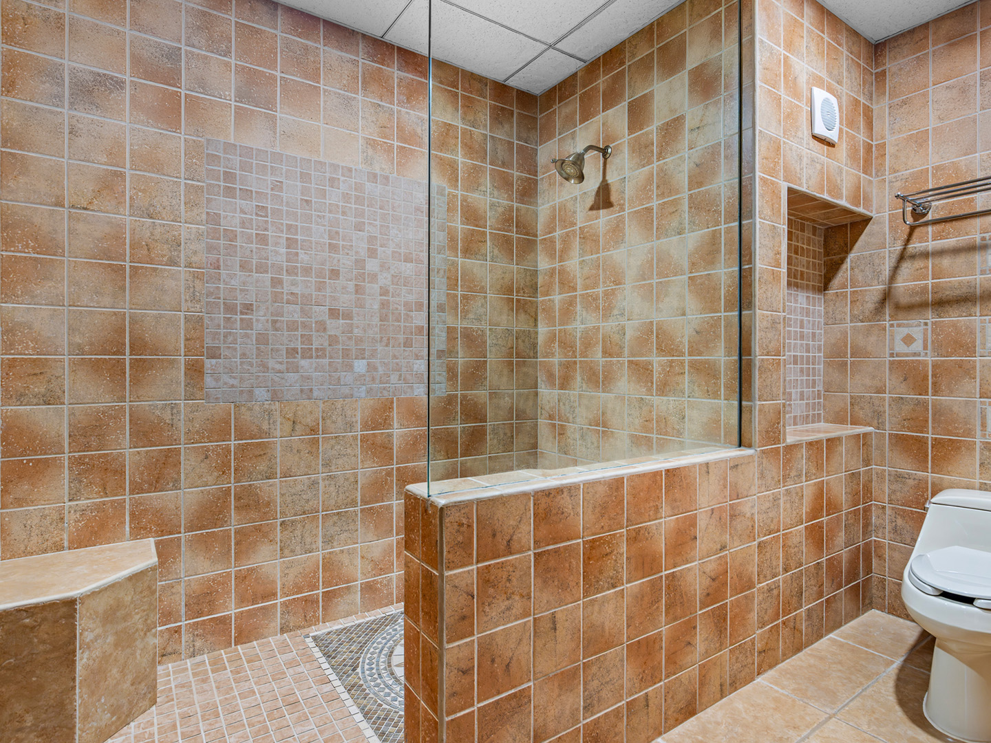 Spacious tiled walk-in shower with built-in bench.