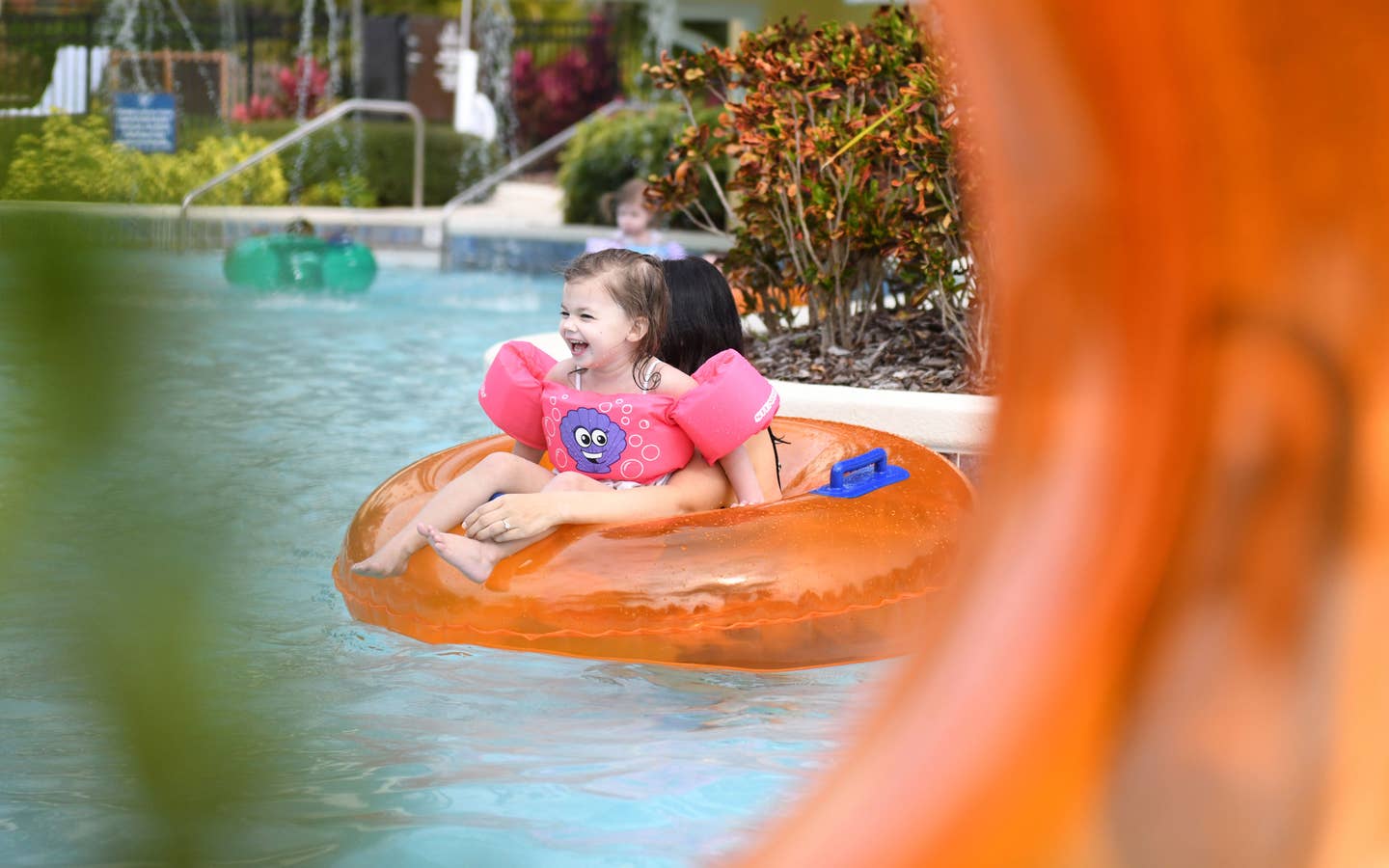 Young girl and mom floating down lazy river in inner tube at Orange Lake Resort near Orlando, Florida