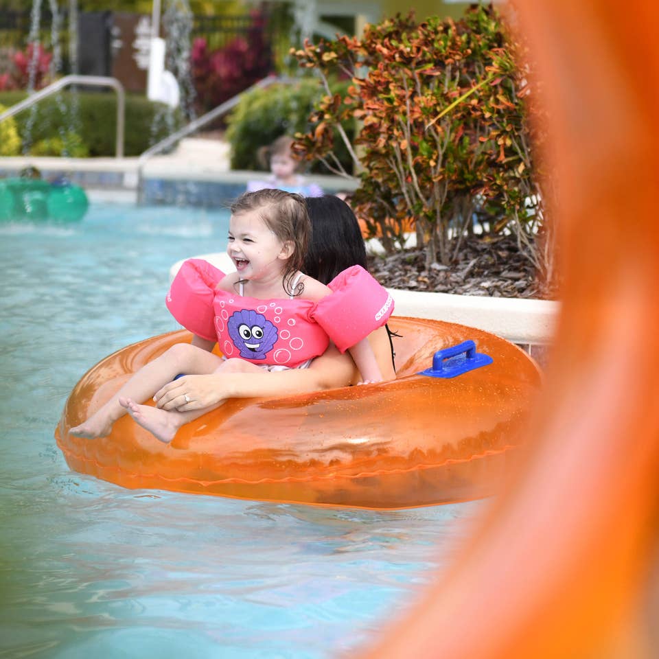 Young girl and mom floating down lazy river in inner tube at Orange Lake Resort near Orlando, Florida