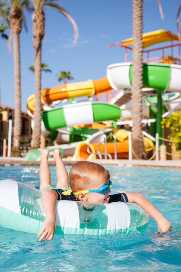 Young child floating in pool with a view of Splash Canyon waterslides at Scottsdale Resort in Arizona.