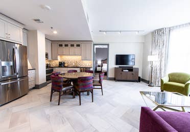 Signature Collection two bedroom villa living area with TV, dining area and full kitchen at New Orleans Resort in Louisiana.