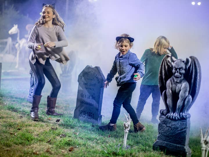 Children doing Halloween-themed scavenger hunt outdoors surrounded by fog.