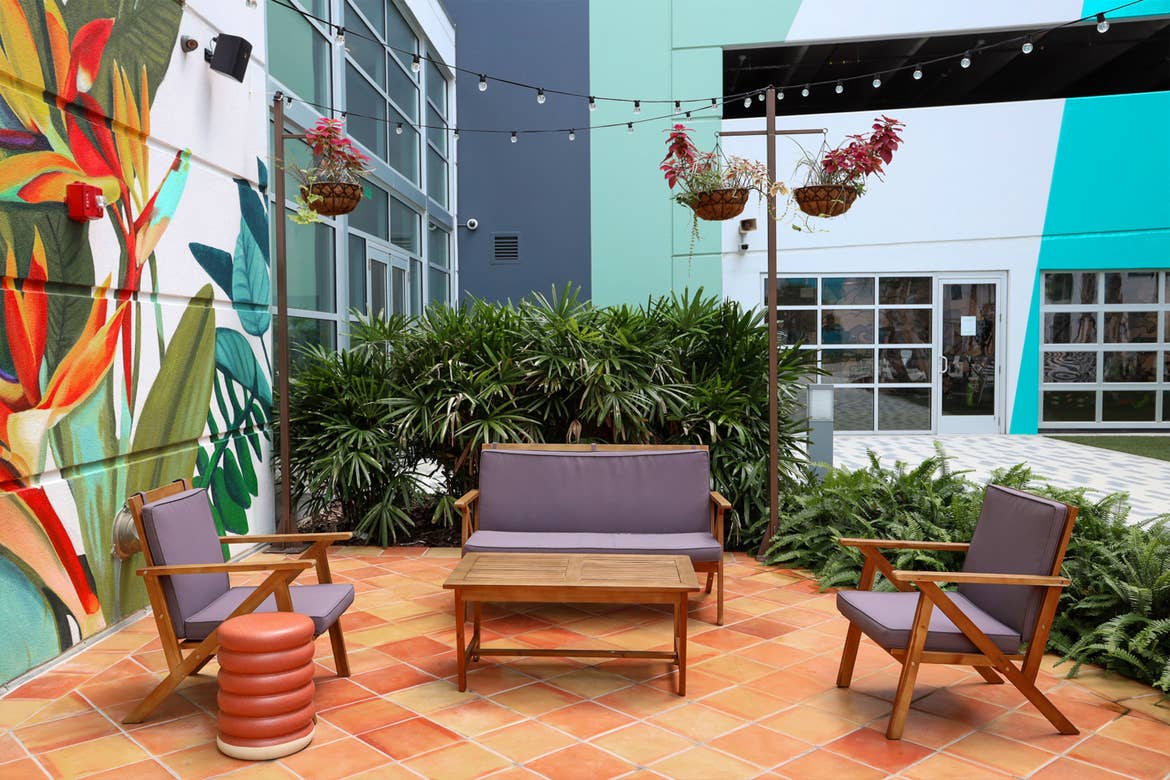 A set of patio chairs set outdoors surrounded by mural-covered exterior walls.
