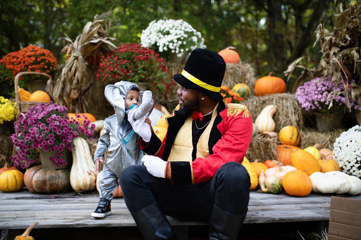Tina's husband and young son dressed up in costumes in front of the fall decorations at Falladays at Villages Resort.