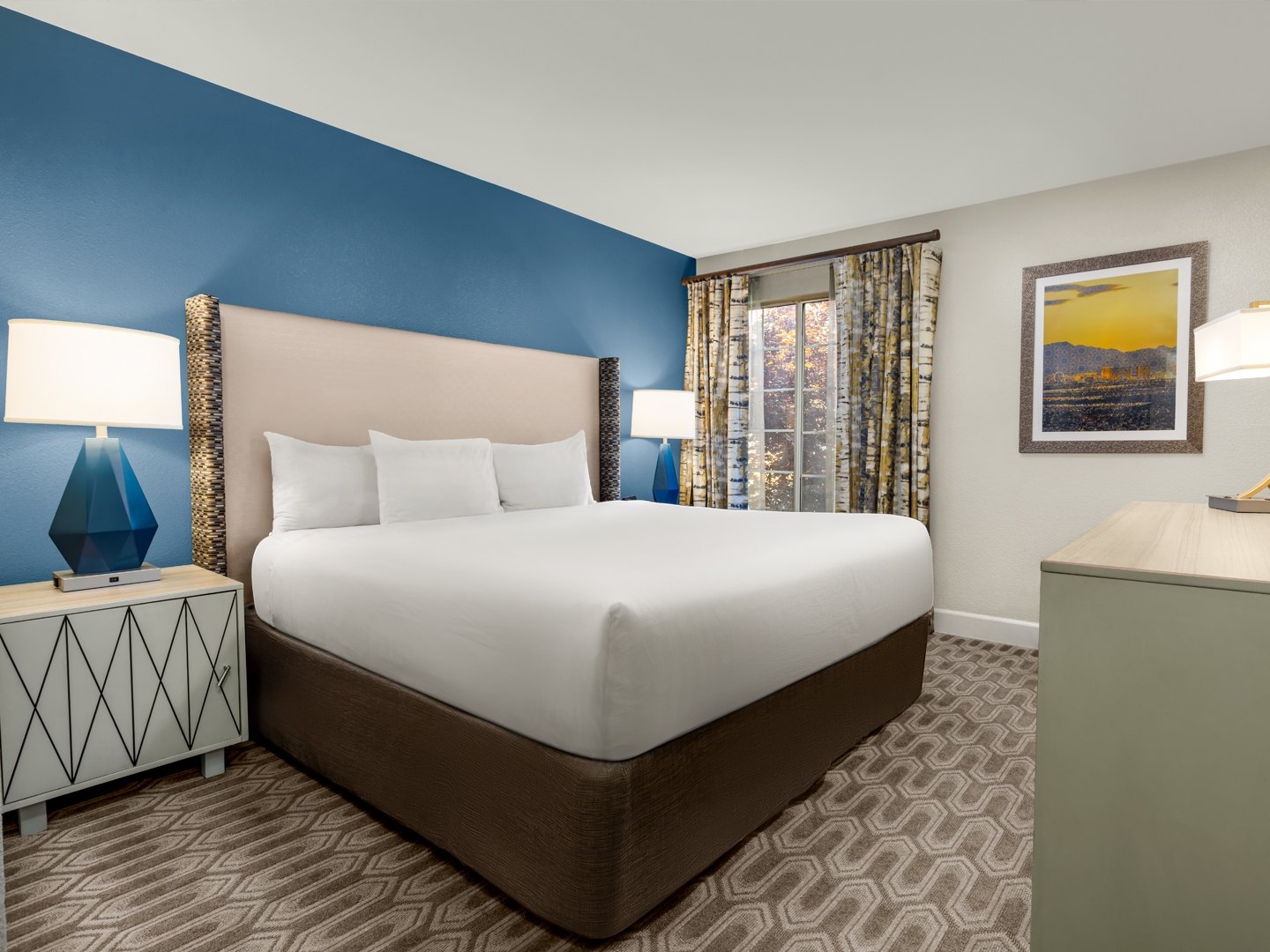 Bright bedroom with modern decor and blue accent wall.
