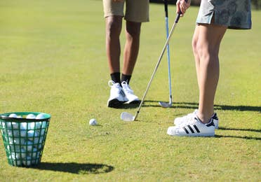 Two golfers putting.