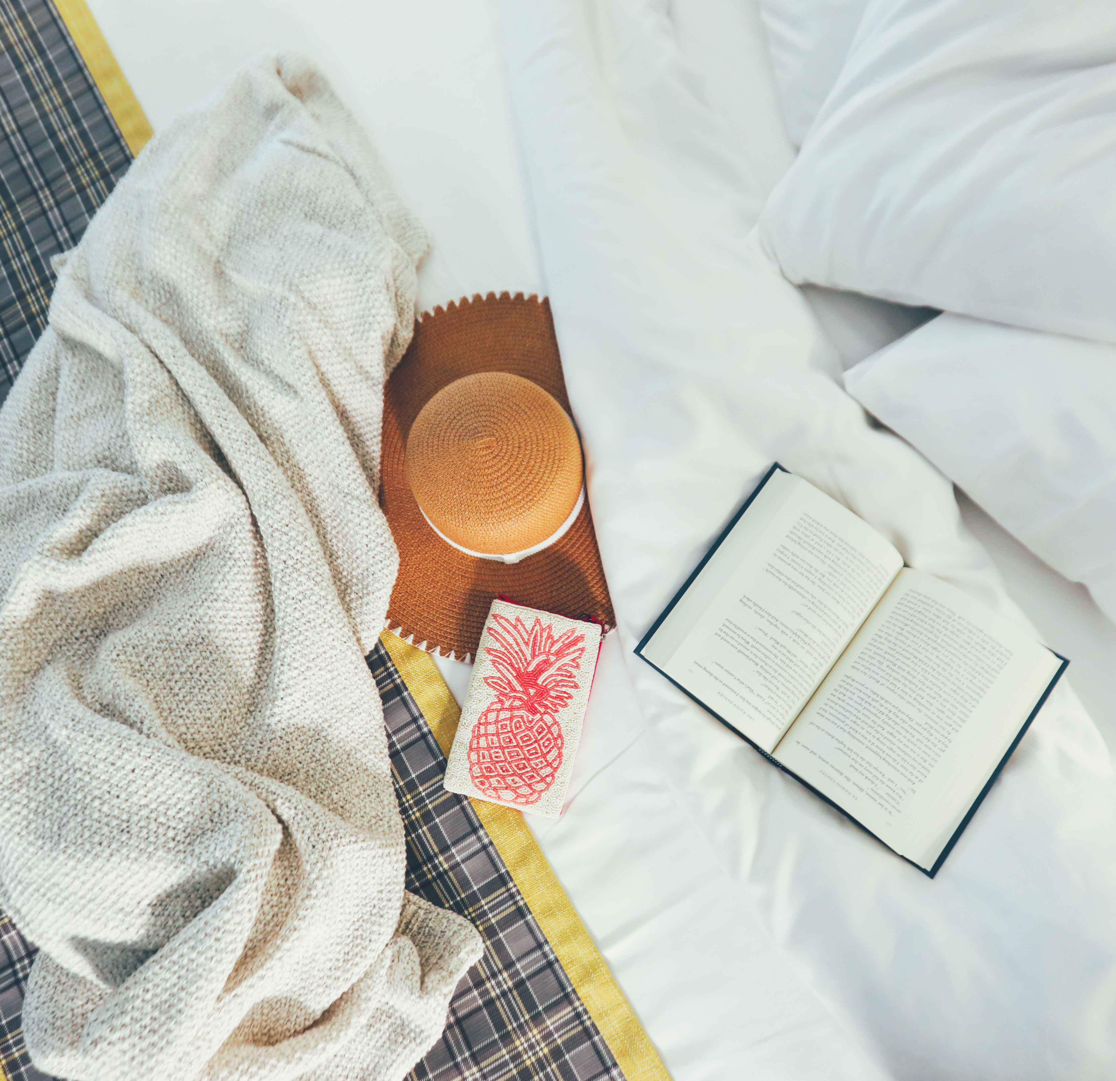 Closeup of book, throw blanket, and sun hat on top of bed in a villa in River Island at Orange Lake Resort near Orlando, Florida