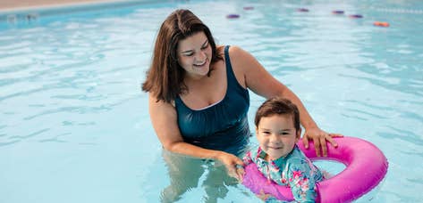 Adult helping child float in outdoor pool at Holiday Hills Resort in Branson, Missouri.