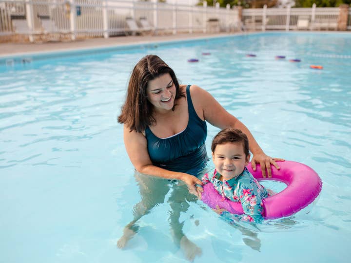 Adult helping child float in outdoor pool at Holiday Hills Resort in Branson, Missouri.