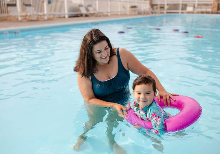 Adult helping child float in outdoor pool at Holiday Hills Resort in Branson, Missouri.