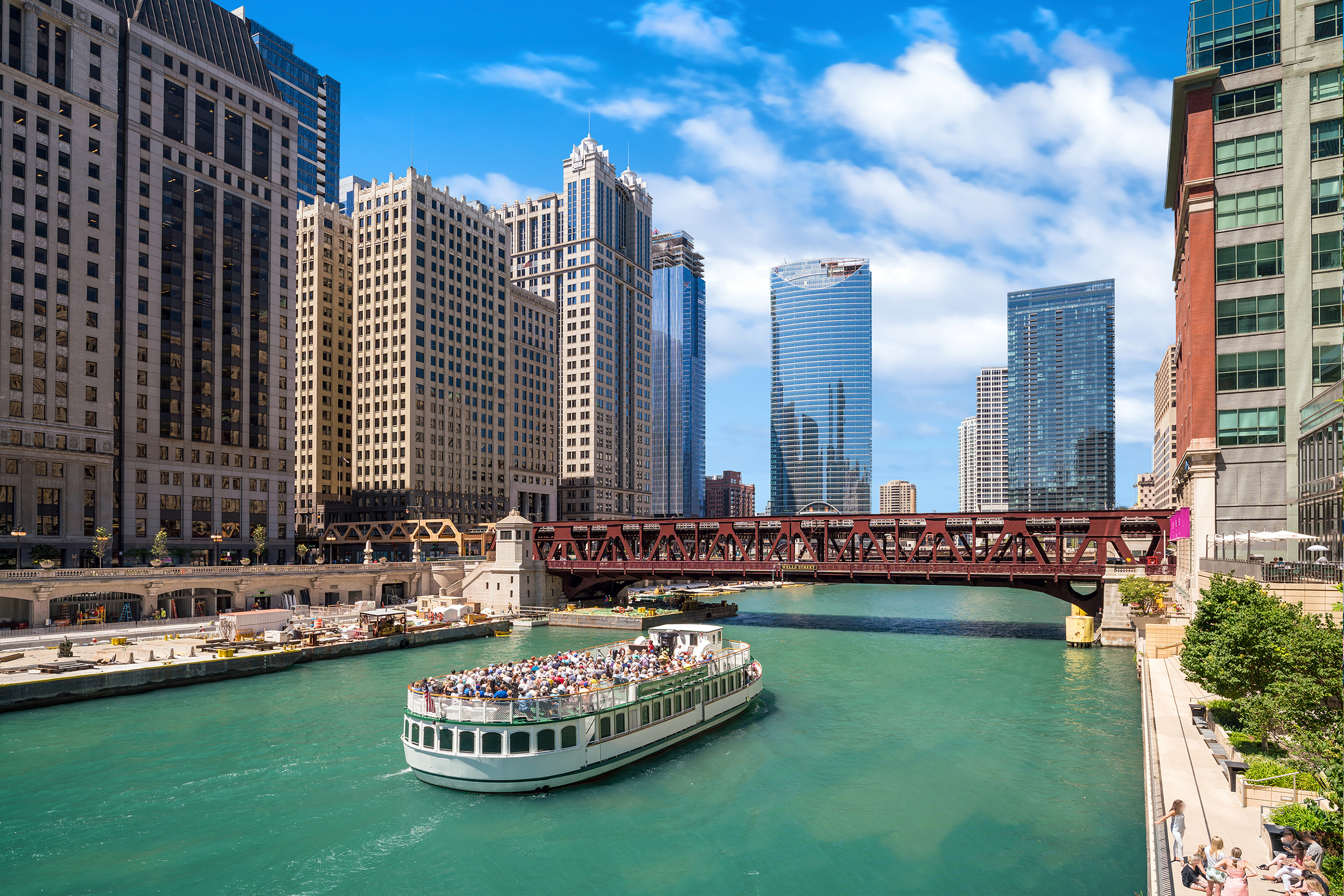 A tour boat makes its way down the Chicago River under iconic bridges and skyscrapers.