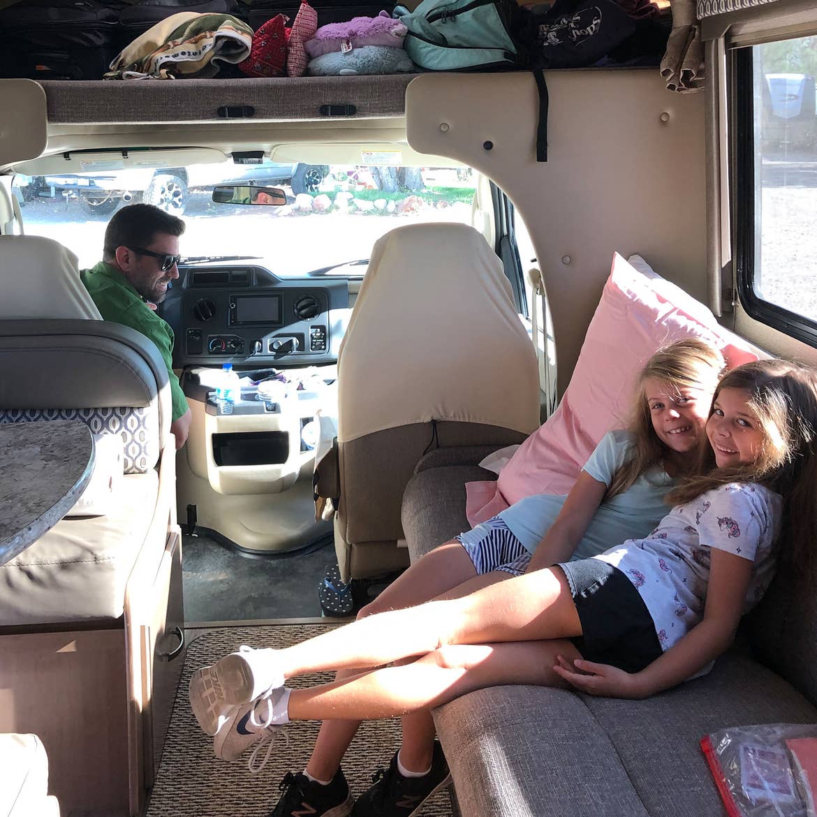 Josh (left) and their daughters (right) seated in their RV rental ready for departure.