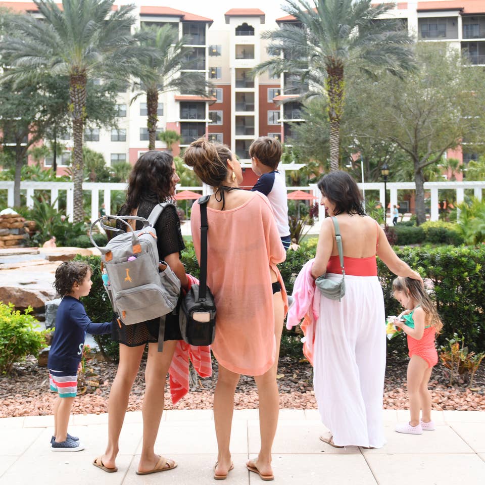 Family standing outside of a large resort building with large palm trees and tropical plants