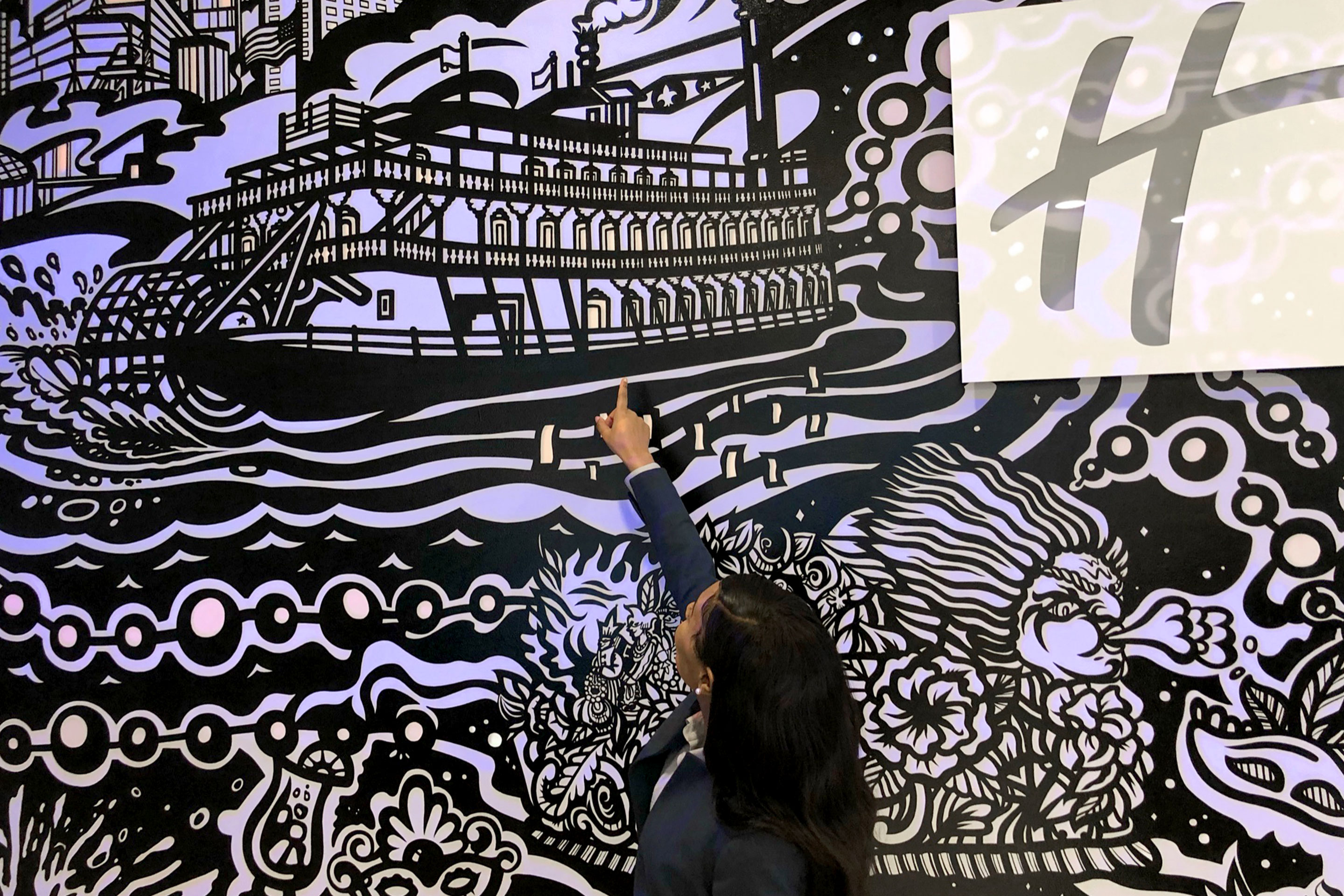 An HICV Team member greets guests in front of our lobby mural sharing local history at our resort in New Orleans, Louisiana.