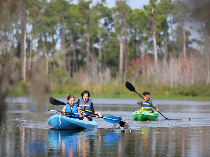 Kids kayaking in lake with watersport rentals at Orange Lake Resort near Orlando, Florida.