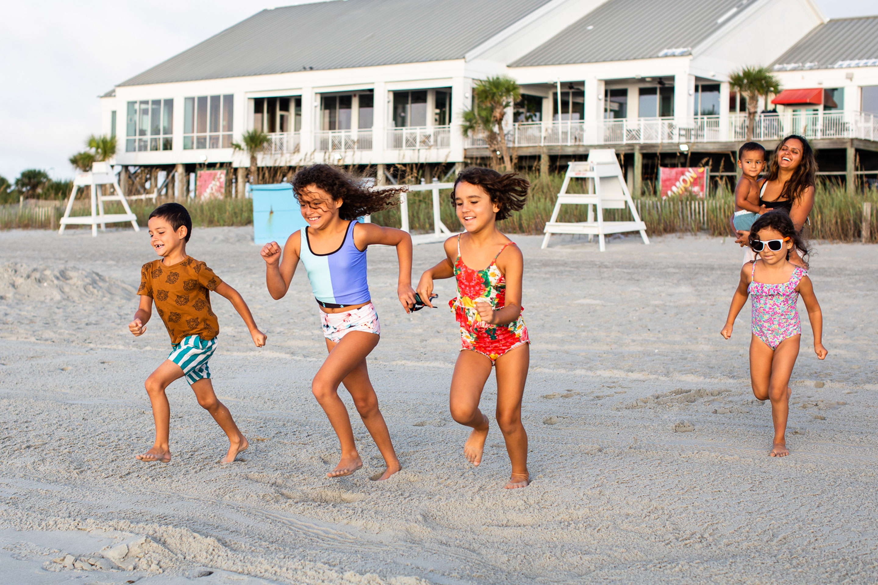Brenda and her family run from their resort to the beach in swimwear.