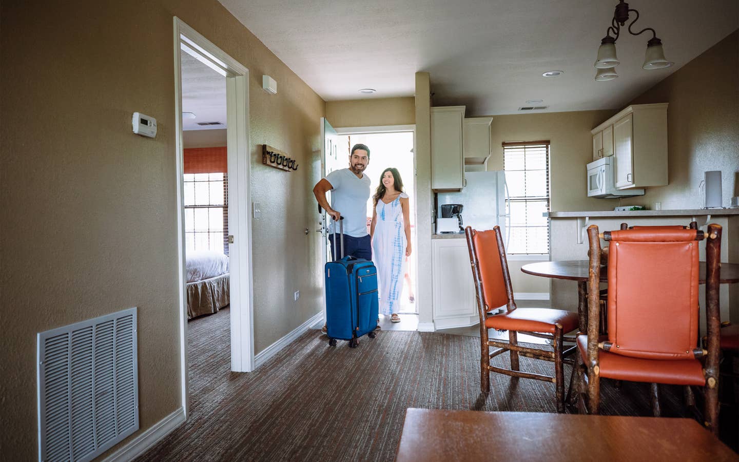 Two guests walking into a villa with their luggage at Fox River Resort in Sheridan, Illinois.