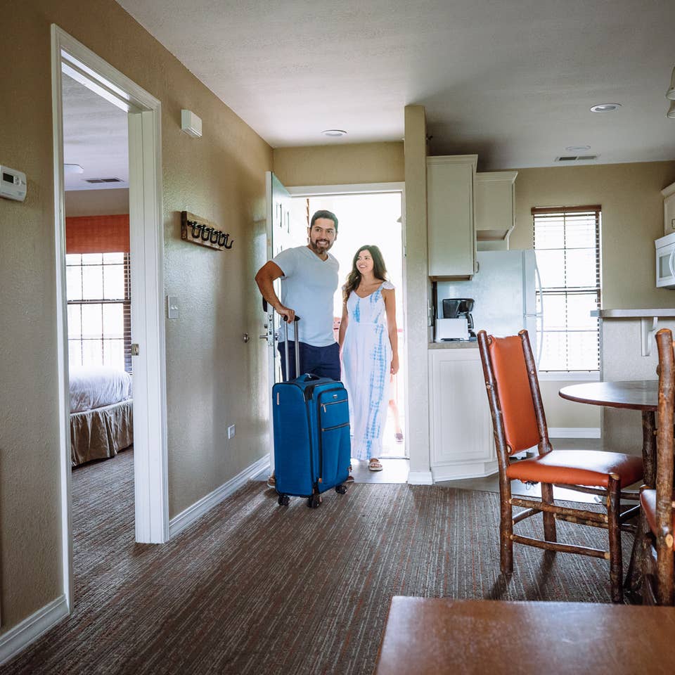 Two guests walking into a villa with their luggage at Fox River Resort in Sheridan, Illinois.