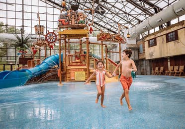 Two kids running in Pirate's Cay waterpark at Fox River Resort in Sheridan, Illinois.