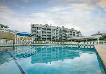 Outdoor pool and sun chairs with view of property building at Hill Country Resort in Canyon Lake, Texas.