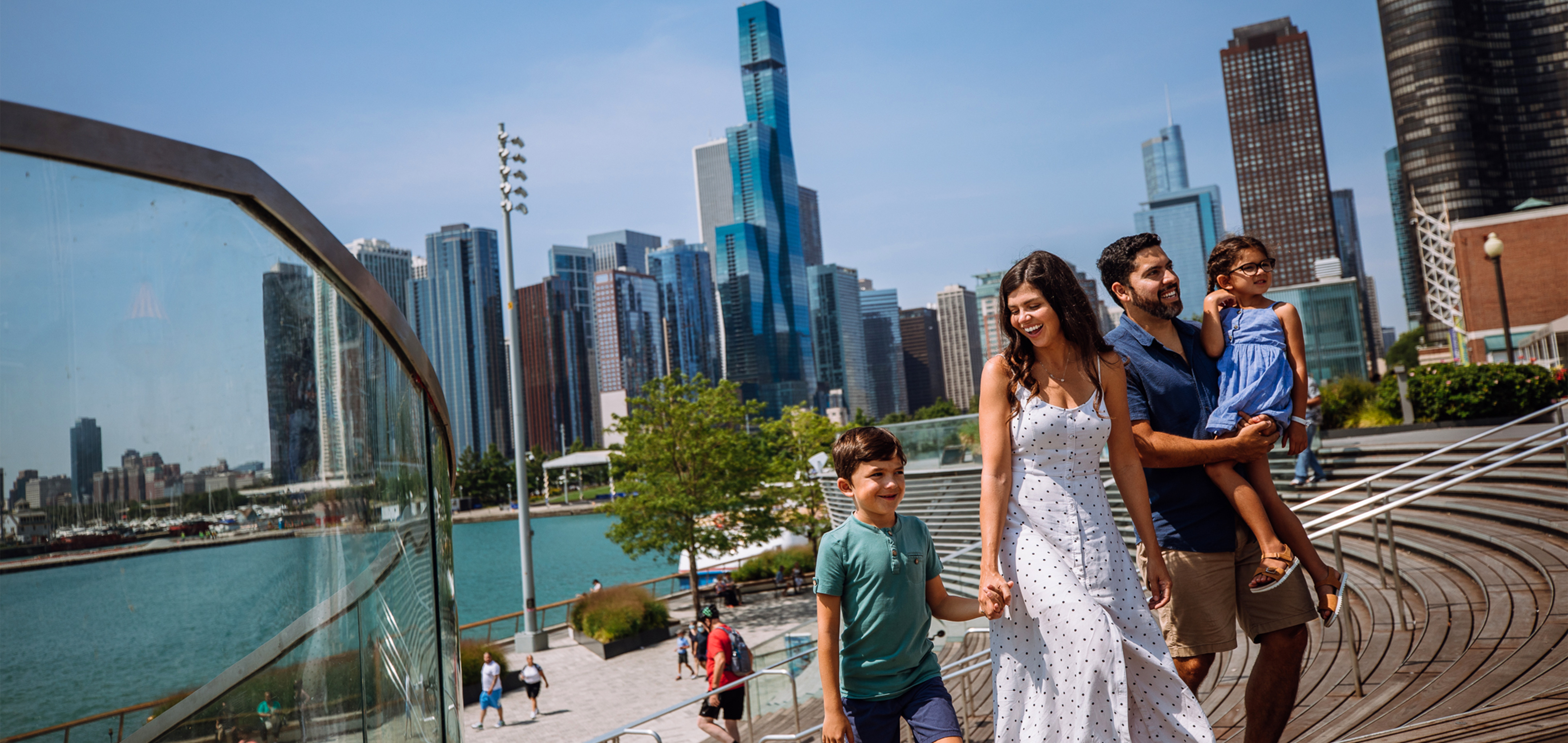 A woman, a man, a young boy and girl walk near the Chicago Skyline.