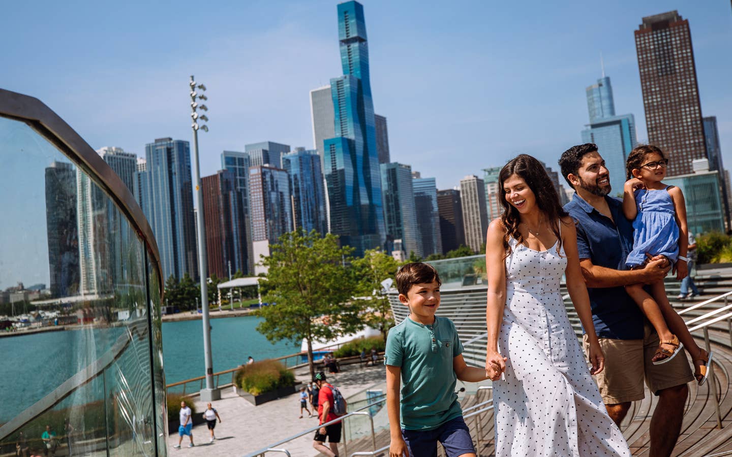 A woman, a man, a young boy and girl walk near the Chicago Skyline.
