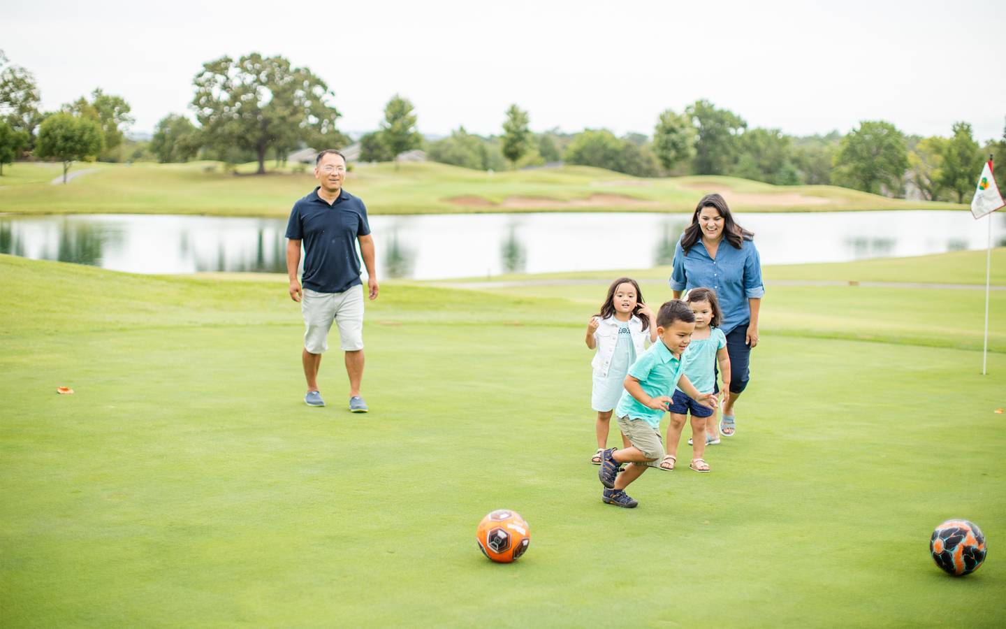 Family playing soccer near a lake
