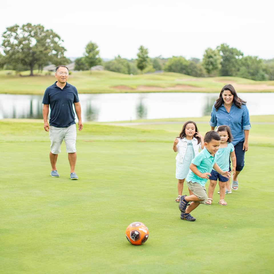 Family playing soccer near a lake