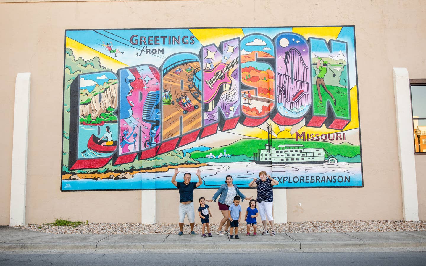 Family in front of Greetings from Branson sign near Holiday Hills Resort.