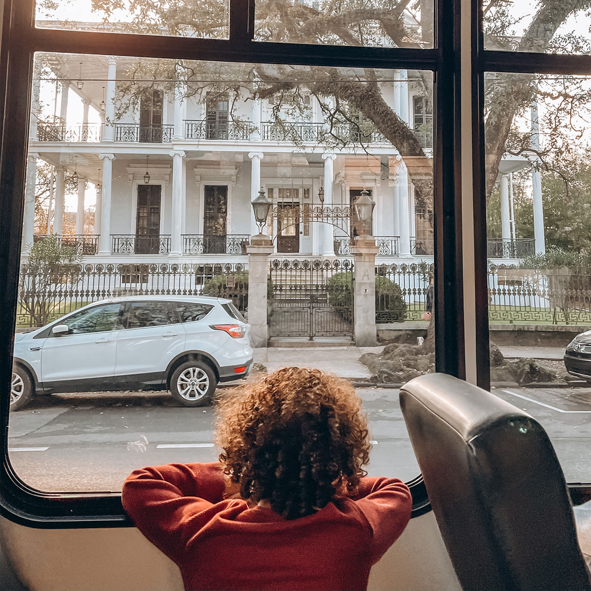 Featured Contributor, Sally Butan of @butanclan's son, Alex, looks out a bus window at the exterior of a white house in the Garden District of New Orleans, Louisiana.