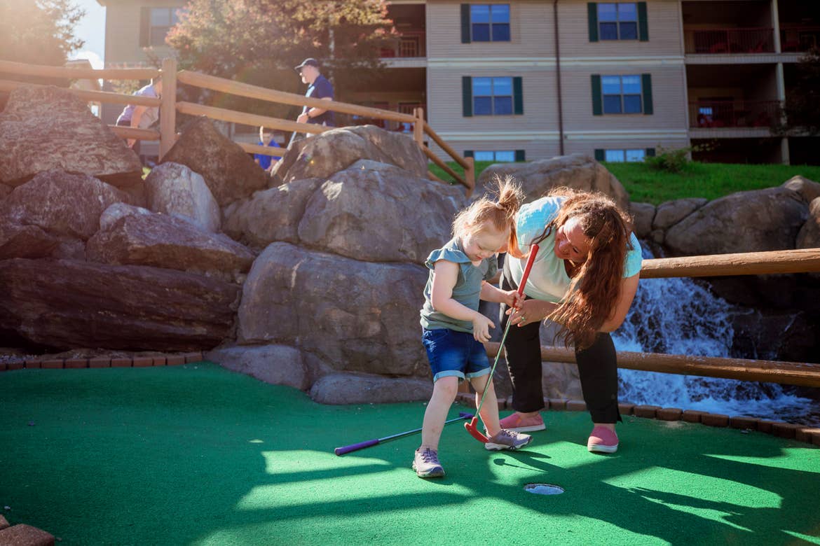 A young girl (left) and woman (right) play on a mini golf course.