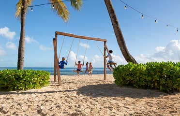 Three kids the beach swinging on a swingset at Royal Cancun Resort in Mexico.